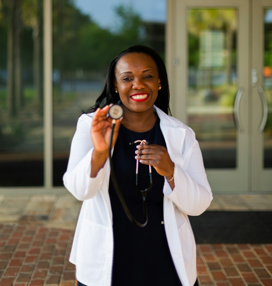 Smiling clinician in a white coat holding a stethoscope outside a care centre